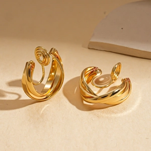 Macro detail of high-shine gold-plated curved metal earrings with reflective mirror finish