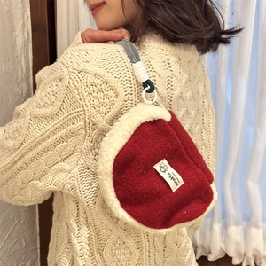 Detailed view of plush red shell bag with white faux fur trim and braided rope handle