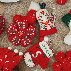 Handmade wool felt Christmas ornaments with stockings and gloves on burlap background