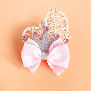 Close-up of pink ribbon bow hair clip with silver glitter crown and pink crystals