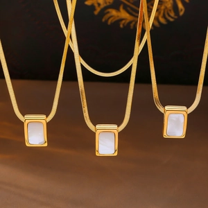 Three gold snake chains with square mother of pearl pendants in a minimalist design