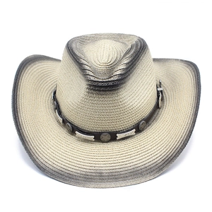 Close-up of beige straw cowboy hat with vintage gray edges and star studded leather band