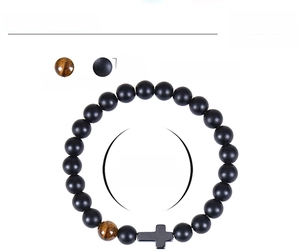 Detail view of 8mm matte black beads and tiger eye bracelet with a cross charm