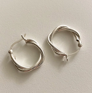 Close-up of geometric twisted S925 sterling silver hoop earrings with clear hallmark