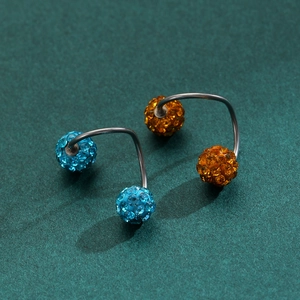 Macro shot of curved barbell piercings with crystal pave balls in blue and amber orange