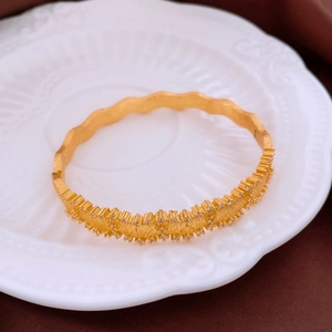 Detailed close-up of a matte gold bangle with micro-pave white zircons on porcelain