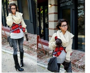 Detail view of a beige chunky knit scarf styled with high boots and ripped skinny jeans
