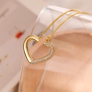 Close-up of gold heart pendant necklace with asymmetrical crystal pavé on fine chain