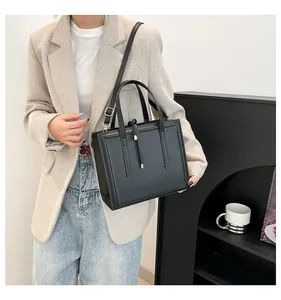 Détail du sac cabas en cuir noir avec pampille en métal doré et bandoulière réglable