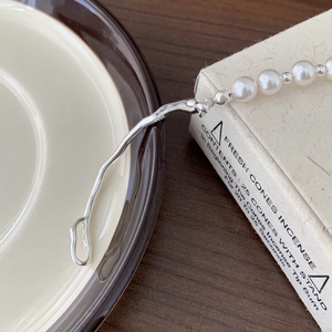 Close-up of S925 sterling silver stamp on an elegant pearl bracelet with irregular metal link