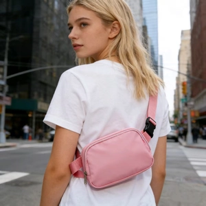Pink waterproof nylon waist bag worn by model in an urban outdoor street setting