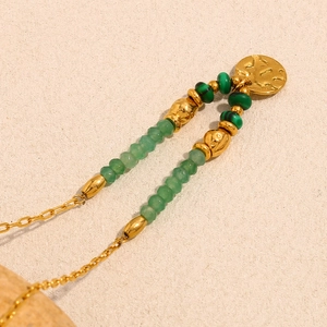 Détail du collier plaqué or 18 carats avec perles vertes et pendentif disque d'or martelé