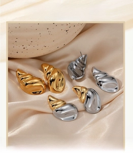 Detailed macro view of conch-shaped stainless steel earrings in gold and silver finishes