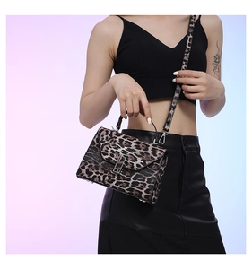 Detail of leopard print handbag with metal clasp and detachable strap on model