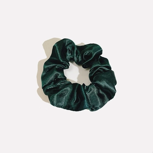Detailed view of dark green satin scrunchie showing glossy texture and elegant fabric folds
