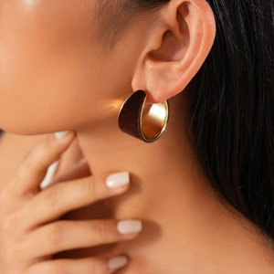 Close-up of vintage golden C-shape hoop earrings with brown flocking on female model