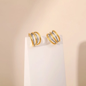 Detailed close-up of mixed gold and silver multi-layer C-shaped minimalist earrings