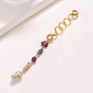 Detailed view of golden snake-shaped hair rings with floral charms and pearls