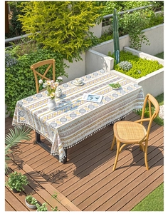 Detail of bohemian linen tablecloth featuring yellow geometric patterns and white tassels