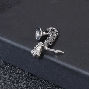 Close-up of polished silver saxophone pendant showing intricate musical instrument details