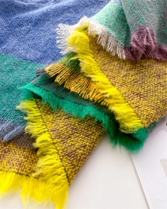 Close-up of multicolor plaid scarf with tassels showing soft fringe and knit texture
