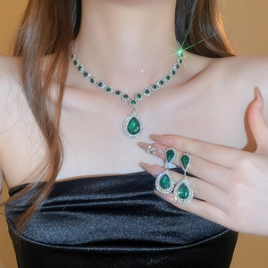 Luxury emerald teardrop necklace and earring set on model in elegant black dress