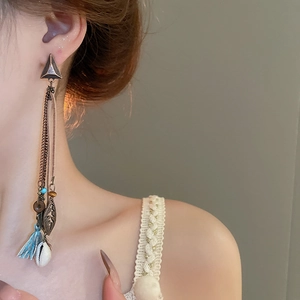 Detail of bohemian tassel earrings with white shells and beads on a female model