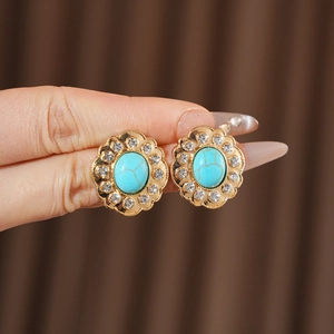 Détail de boucles d'oreilles fleur vintage avec pierre turquoise et strass brillants