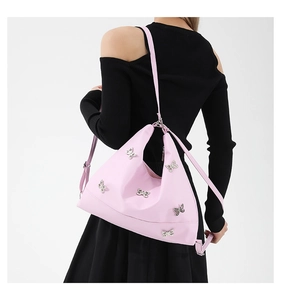 Detailed back view of pink crossbody bag with silver butterfly charm and adjustable strap