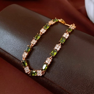 Macro detail of 18k gold plated vintage bracelet with emerald green square gemstones