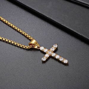 Detailed close-up of golden hip hop cross pendant with micro-paved cubic zirconia on black background