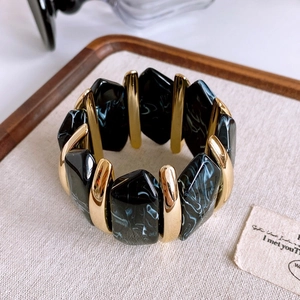Detail of vintage stretch bracelet with black marble resin and gold metal accents