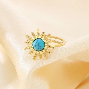 Detail of sunflower ring with turquoise inlay on champagne silk, bohemian style