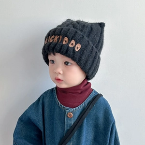Dettaglio del berretto in maglia nera per bambini con ricamo e trama calda
