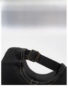 Detail of adjustable metal buckle on vintage washed black denim baseball cap with stitching