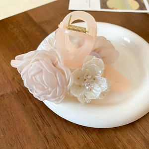 Detail showing pink translucent hair claw clip with fabric rose and pearlescent flower