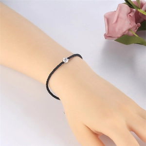 Close-up of minimalist black braided couple bracelet with single diamond pendant on wrist
