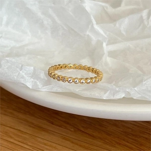 Macro detail of gold eternity band with pave zircon stones on a rustic wood surface