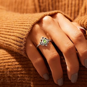 Vintage silver lotus ring with a pear-cut green gemstone shown on a hand