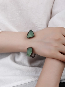 Detail of adjustable antique bronze bracelet featuring raw green crystal stones on wrist
