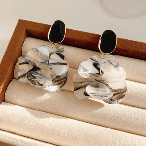 Macro detail of French resin flower earrings with black and white marble petals in jewelry box