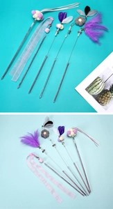 Close-up of cat wand toy with purple feathers, pink ribbons, plush balls and metal bells