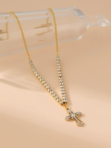 Detailed view of a gold cross necklace with sparkling zircons hanging on a glass display