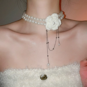Détail d'un collier ras du cou en perles avec fleur au crochet et chaînes pendantes