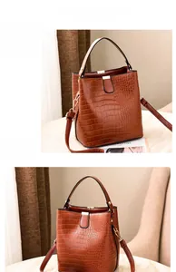 Detailed close-up of brown crocodile pattern bucket bag with golden hardware and clasp