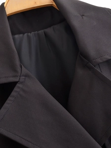 Detailed view of black double-breasted trench coat neckline and twill fabric texture