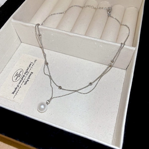 Détail d'un collier double épaisseur avec pendentif perle et fine chaîne argentée