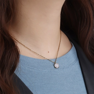 Minimalist gold necklace with a round pink crystal stone pendant worn on a female model