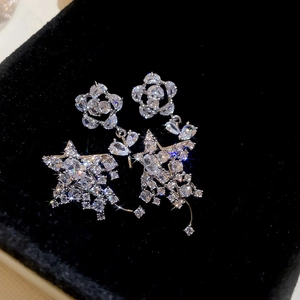 Gros plan de boucles d'oreilles fleurs et étoiles en argent et zircon sur écrin