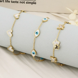 Detailed shot of golden titanium bracelets with evil eye, butterfly, and heart shell charms